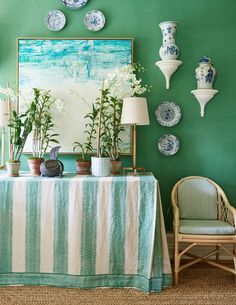 a dining room with green walls and plates hanging on the wall above it's table