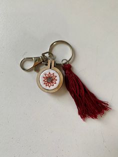 a red tasseled keychain with a flower on the front and side