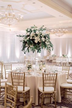 an elegant wedding reception setup with white flowers and greenery in tall centerpieces