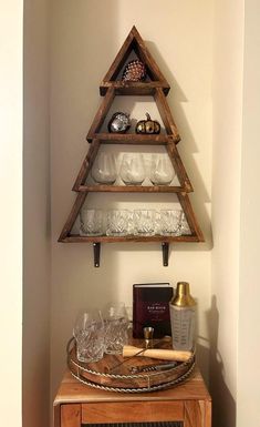 a wooden shelf with wine glasses and other items on it in the corner of a room