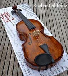 a cake made to look like a violin on top of sheet music paper with the words, enchanted icing