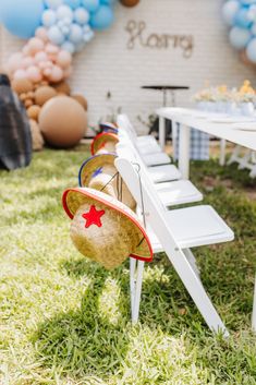 an outdoor party with balloons and decorations on the grass in front of a table set up for