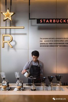 a man standing behind a counter filled with coffee