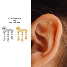 three pairs of ear piercings with chain links and dangling balls on each side of the ear