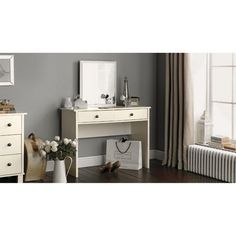 a white desk with two drawers and a mirror on top of it next to a radiator