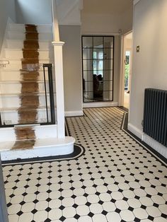 an empty room with black and white flooring next to a radiator on the wall