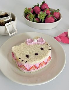 a hello kitty cake on a plate with strawberries