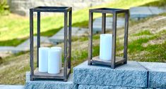 two white candles sitting on top of a stone block