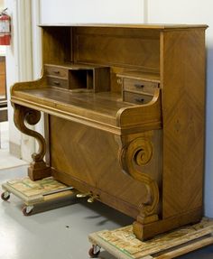 an old wooden desk sitting on top of a dolly in a room with blue walls