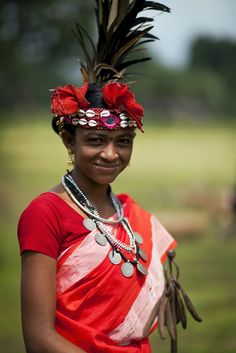 a woman with feathers on her head smiles for the camera while standing in a field