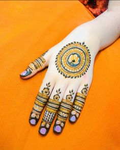 a woman's hand with hennap and tattoos on her hands, sitting on an orange surface