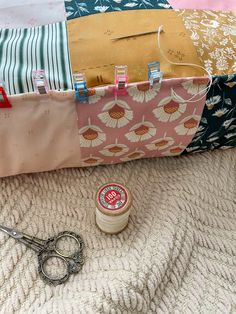 scissors, thread, and fabric on a blanket next to a sewing bag with zippers