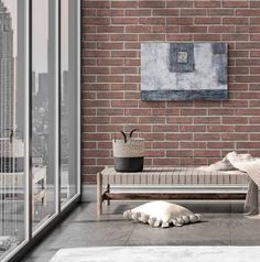 a white dog laying on the floor in front of a brick wall with a painting hanging above it