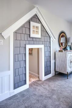 a dog house built into the side of a wall next to a dresser and mirror