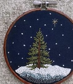 a cross stitch christmas tree with snow on the ground and stars in the night sky