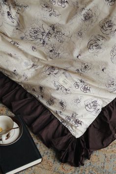 a coffee cup and saucer sitting on top of a bed next to a book