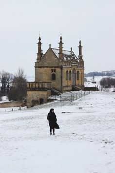 a person walking in the snow near a building