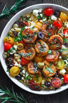 a white bowl filled with pasta salad and olives on top of a wooden table