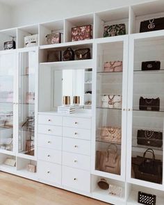 a white closet filled with lots of purses and handbags on top of shelves