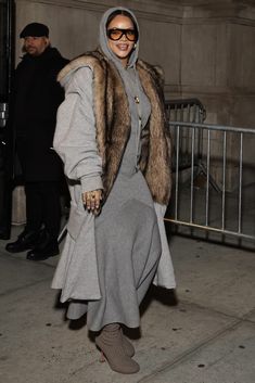 a woman in grey coat and sunglasses walking down the street