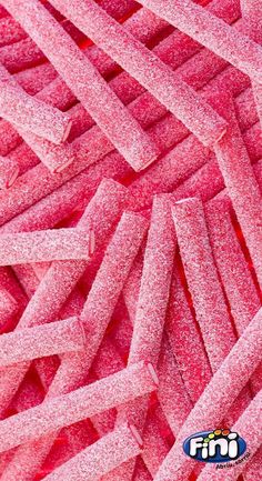 pink candy sticks are stacked together in a large pile, with the word's logo on