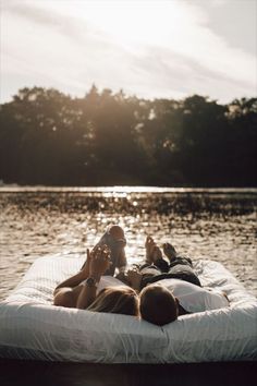 two people laying on a mattress in the water