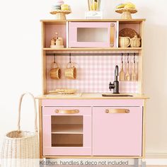 a toy kitchen with pink cabinets and checkered wallpaper on the walls, next to a wicker basket