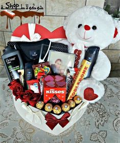 a white teddy bear sitting next to a valentine's day gift basket filled with chocolates and candy