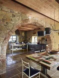 a kitchen with stone walls and an arched doorway leading to the dining room area is shown