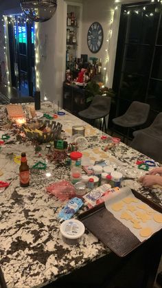 a kitchen counter covered in cookies and frosting next to a table with candles on it