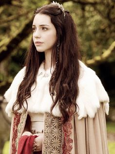 a woman dressed in medieval clothing standing next to a tree