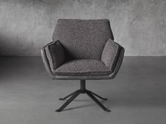 an upholstered chair sits in front of a concrete wall with a black base