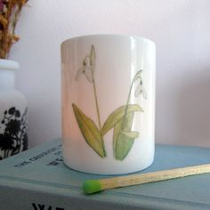 a white coffee cup sitting on top of a stack of books next to a pencil