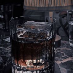 a glass filled with ice sitting on top of a table