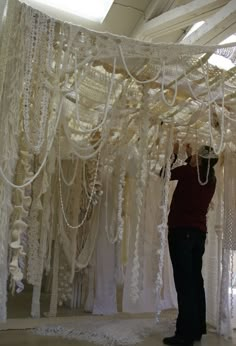 a man standing in front of a white curtain covered with chains and beads on the ceiling