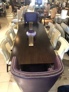 a dining room table with purple chairs around it and lots of tables in the background