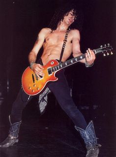 a shirtless man playing an electric guitar