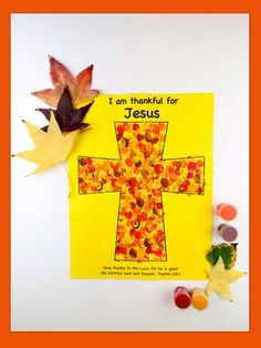 a cross made out of paper with leaves on the side and an orange frame around it