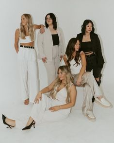 four women in white outfits posing for the camera