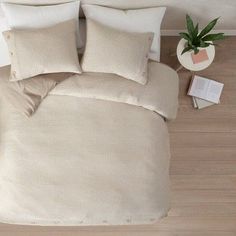 an overhead view of a bed with two pillows and a plant on the floor next to it