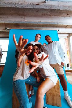 a group of young people posing for a photo in front of a blue wall with their hands up