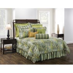 a bed with green and yellow comforters in a bedroom next to a night stand