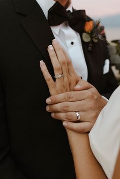 the bride and groom are holding each other's hands with wedding rings on their fingers