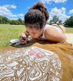 a woman is laying on the ground drawing with her hands and looking at something in front of her