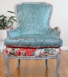 a blue chair sitting on top of a wooden floor next to a potted plant