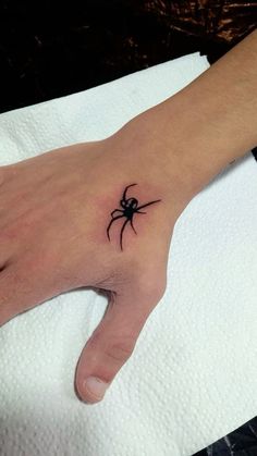 a person's hand with a small spider tattoo on it