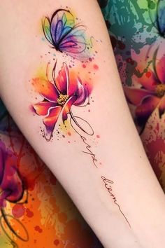 a woman's arm with colorful watercolor flowers on it and the word love written in