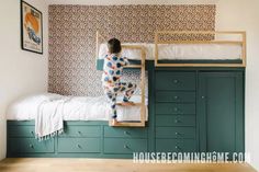 a person standing on top of a bunk bed in a room with green cabinets and drawers