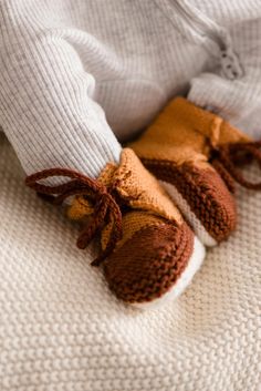 a baby's feet wearing brown and white knitted shoes