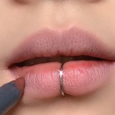 a close up of a woman's lips with a ring on the lip and her finger